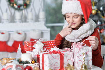  happy girl in Santa hat sitting  with Christmas presents