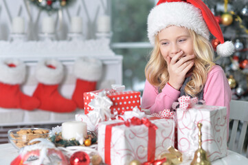 happy girl in Santa hat sitting  with Christmas presents