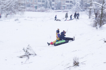 Fototapeta na wymiar people enjoying the streets of snow. ROLLER COASTER IS THE BEST ENTERTAINMENT IN WINTER. winter leisure, active lifestyles, tobogganing. Focus Blured in motion. Abstract blurry winter image.