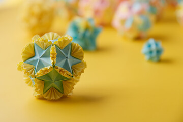 Set of multicolor handmade modular origami balls or Kusudama Isolated on yellow background. Visual art, geometry, art of paper folding, paper crafts. Close up, selective focus, copy space.