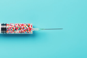 Syringe with colorful balloons on a blue background with free space.