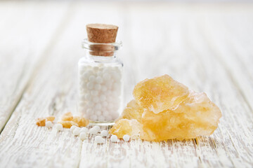 Sulphur crystal with homeopathic globules on white wooden background