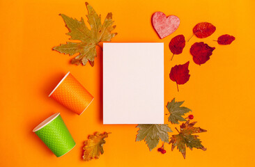 two cardboard coffee cups, an autumn-themed mockup with leaves on an orange background,top view