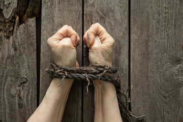 tied hands with rope of old woman on wooden background