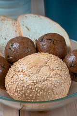 fresh delicious buns and slices of wheat bread on wooden kitchen table