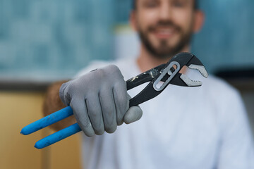 Necessary hand tool. Close up shot of hand of young repairman holding a pipe wrench