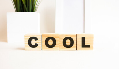 Wooden cubes with letters on a white table. The word is COOL. White background.