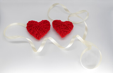 two red knitted hearts with ribbon on a white background. happy valentines day idea.