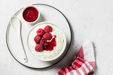 Almond milk rice pudding with raspberry sauce  in a bowl. Top view, space for text.
