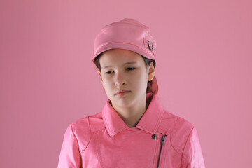 portrait of a teenage girl in a pink leather jacket on a pink background