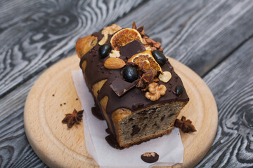 Banana bread garnished with nuts and dried fruits. A slice of bread is visible. Close-up shot.