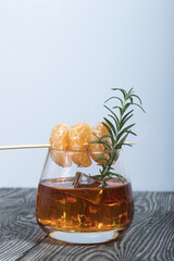 Alcoholic cocktail. Garnished with rosemary slices and tangerine wedges. Close-up shot.
