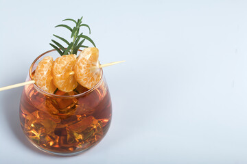 Alcoholic cocktail. Garnished with rosemary slices and tangerine wedges. On a white background. Close-up shot.