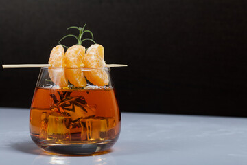 Alcoholic cocktail. Garnished with rosemary slices and tangerine wedges. Close-up shot.