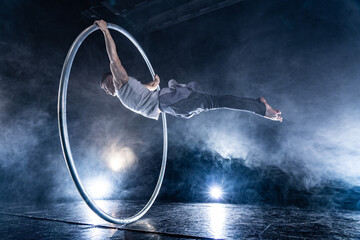 Fototapeta premium Cyr Wheel circus artist on smoked, dark background performing on stage 