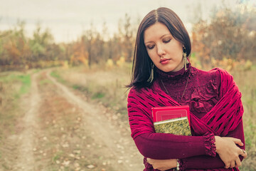 Dark-haired lady In park with old poetry book in her crossed on bosom hands vintage dressed