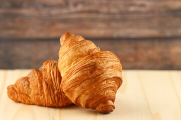 Fresh tasty croissants on wooden background, French pastry.