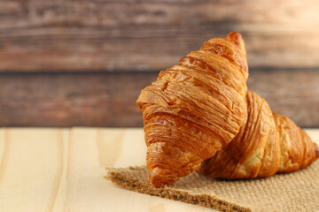 Fresh tasty croissants on wooden background, French pastry.