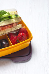 Sandwich in plastic container on wooden background