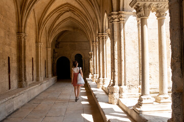 Tourist woman visiting the cloister of the cathedral of Arles, France, - obrazy, fototapety, plakaty