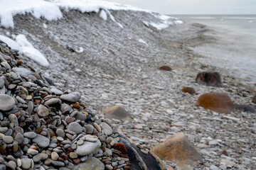 Snow on cobblestone beach with ocean background