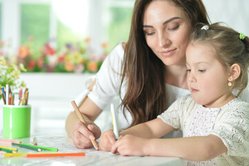 cute girl with mother drawing at the table