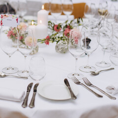 Wedding table in the restaurant decorated with white candles and flowers.