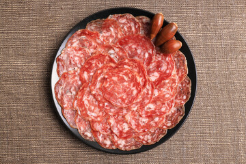 Ration of acorn-fed Iberian sausage in black plate decorated with acorns
