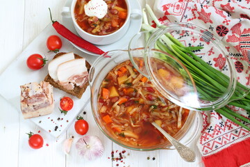 Borsch with bacon, black bread on a white wooden background