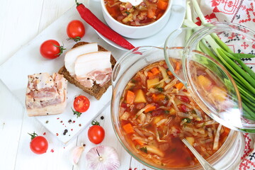 Borsch with bacon, black bread on a white wooden background