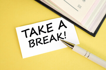 take a break. text on white paper on a yellow background near the pen.
