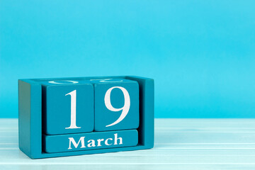 wooden calendar with the date of 
March 19 on a blue wooden background, 
International Week of...