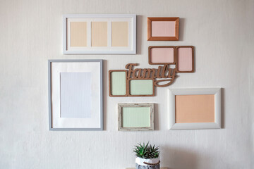 White wall with set of different empty vertical and horizontal picture frames to create family...
