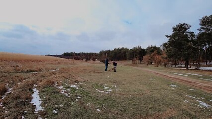 Timelaps man and woman with their beloved dog on leash playing near pine forest. Concept of pet care and loving