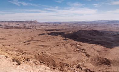 Fototapeta na wymiar view of Mount Ardon and Givat Gaash in the Makhtesh Ramon crater in Israel from the Gaash Overlook with a beautiful partly cloudy sky in the background