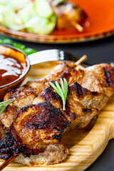 Grilled pork skewers with cucumber salad and barbecue sauce on the cutting board close up vertical photo