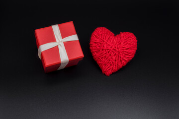 Red box for the holiday. Gift box on a black background with a red heart. New Years, Christmas, Valentine's Day, 8th March birthday gift. minimalism.