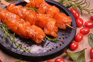 Chicken pieces of kebabs marinated in a red marinade with spices on a dark culinary board, on a...