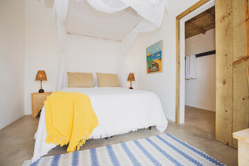 Modern luxury summer holiday or vacation wooden beach house bedroom interior with white bed, bedside table and straw bedside lamp.	