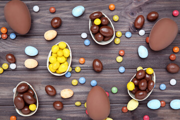 Easter chocolate eggs with candies on brown wooden table