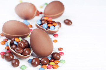 Easter chocolate eggs with candies on white wooden table