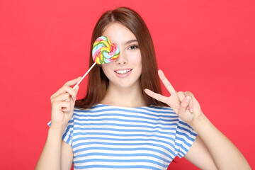 Beautiful girl with lollipop on red background