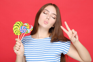 Beautiful girl with colorful lollipops on red background