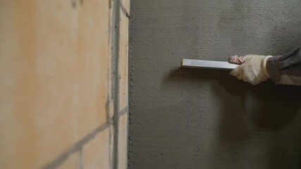 The builders are using triangular steel to smooth the plaster evenly in the walls of the house. concepts of the construction industry with skilled workers. The craftsman evens the putty on the wall.