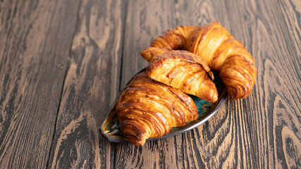 Perfect golden croissants on dark wooden table. Tasty buttery croissants on old wooden table