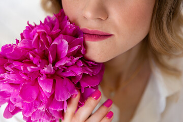 Fototapeta premium woman in shirt, holds bouquet of peonies in her hands. Surprise bouquet of flowers for date, mothers day or valentines day. Skin and lips texture close up