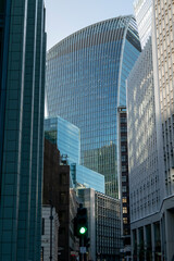 View for variety of tall glass commercial buildings so close together covering the sky and blocking sunlight to lower parts of the streets in London. Overwhelming modern architecture of always growing
