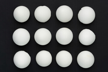 White eggshells are laid out in even rows on a black background. The concept of sameness, equality and equity. The concept of impersonal, stereotyped and unoriginal things, people and phenomena.