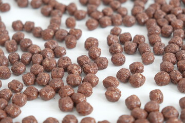 Chocolate corn balls scattered on a white background. Top view. Copy, empty space for text