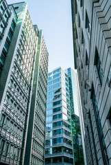 Obraz premium View for variety of tall glass commercial buildings close together covering the sky and blocking sunlight to lower parts of the street. Overwhelming modern architecture of always growing capital city.